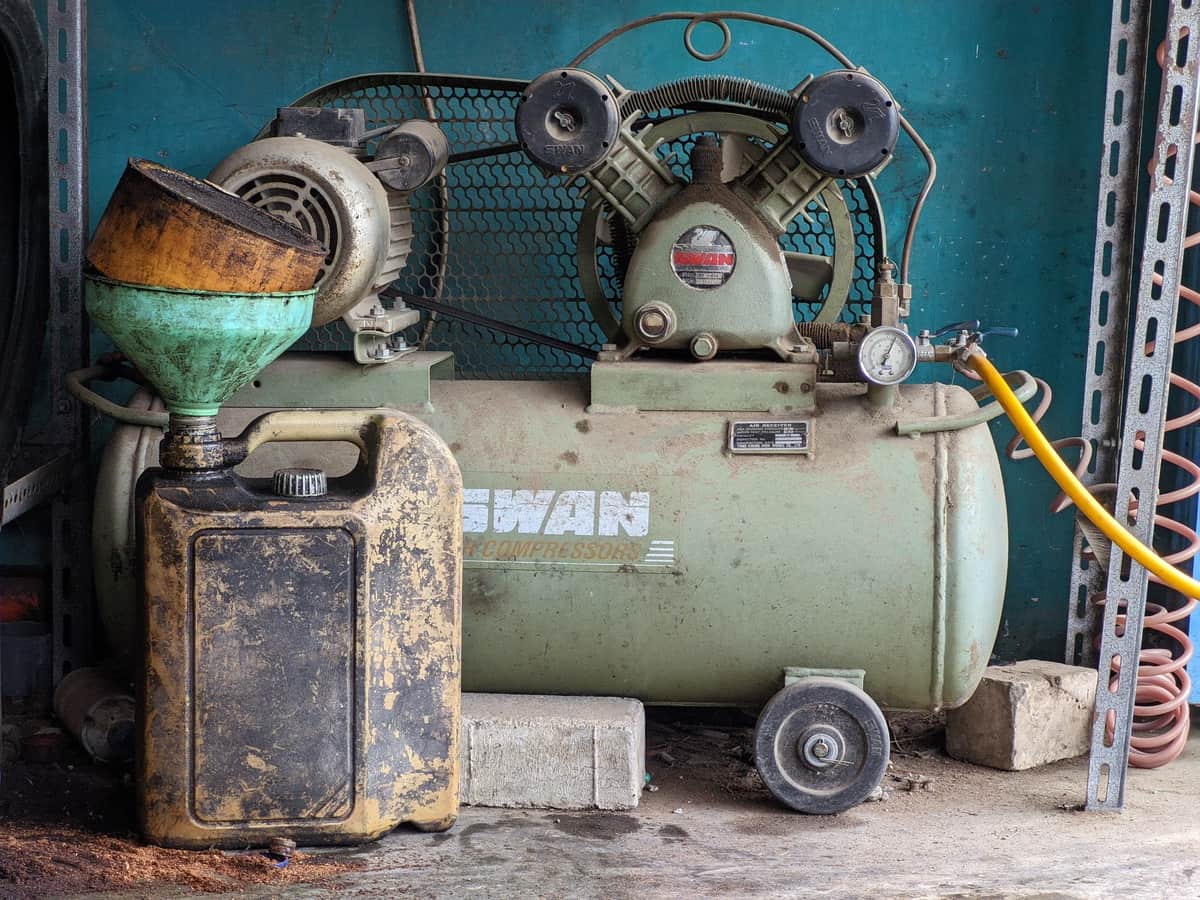 A compressor and oil can on a workshop bench