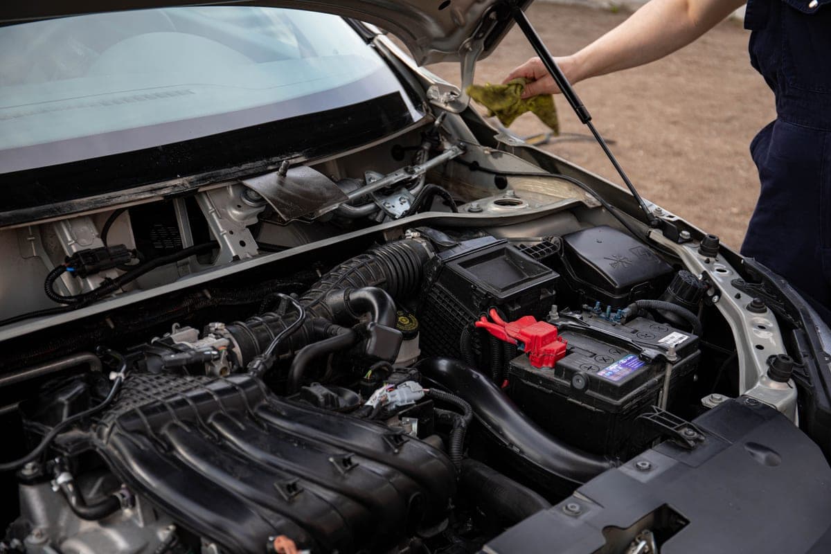 A car battery under an open hood with the terminals exposed