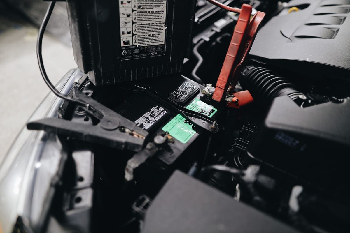 A compact lithium jump starter with its clamps coiled beside it
