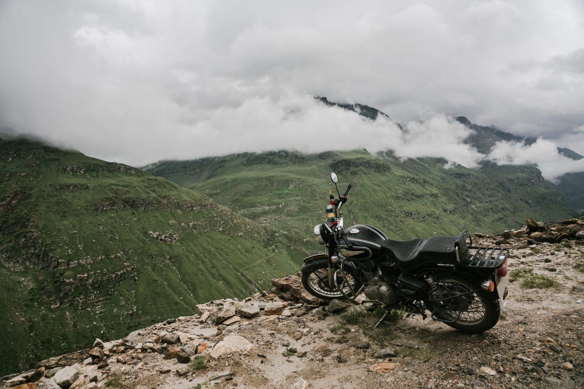 A motorcycle parked on a road above a valley