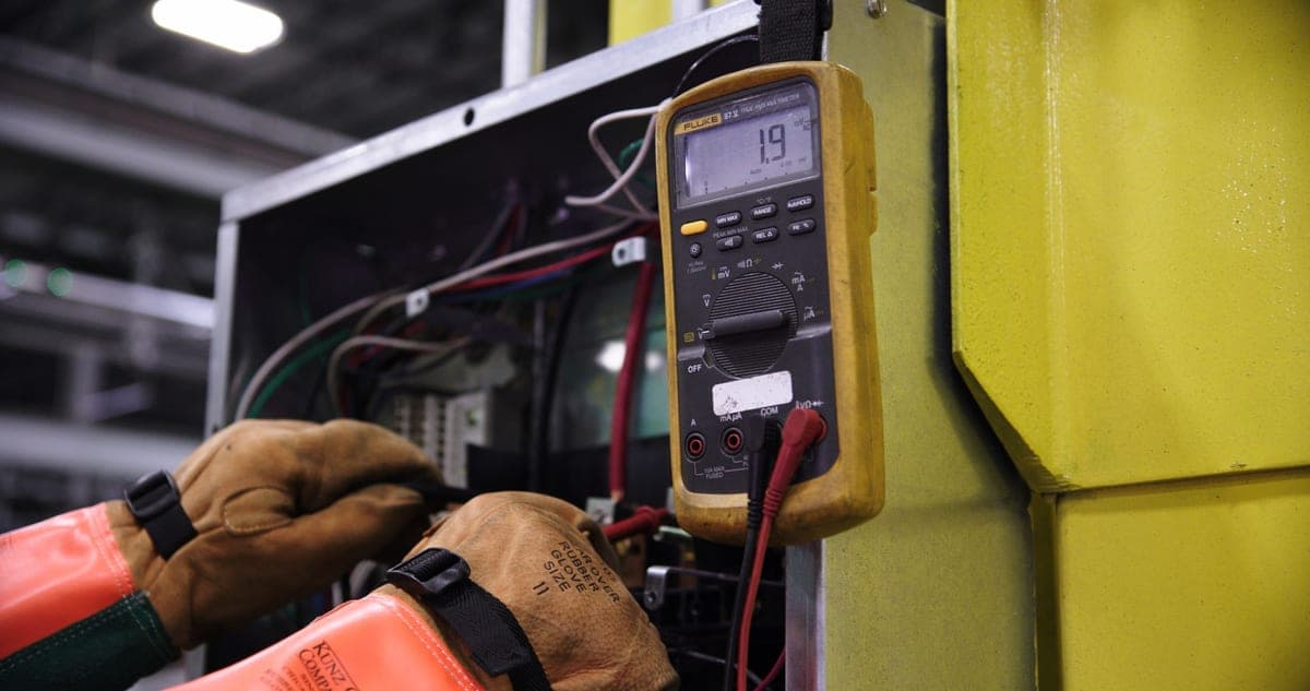 A technician testing an electrical panel with a meter